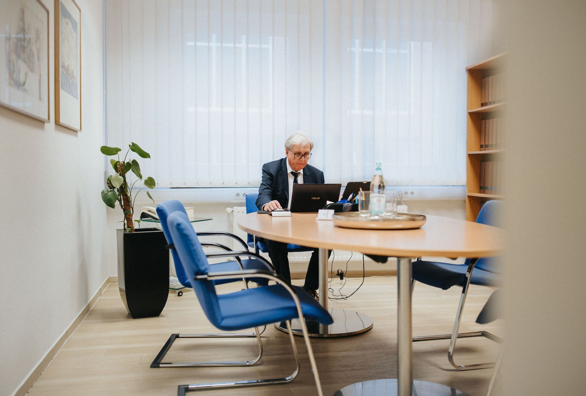 Dr. Rainer Hildebrand sitzt an einem Tisch und benutzt einen Laptop.