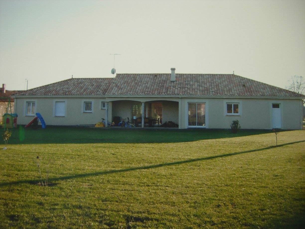 Maison de plain-pied avec un toit de tuiles et un grand jardin gazonné à l'avant.