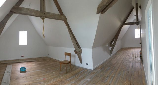 Grenier vide avec poutres apparentes, plancher usé.