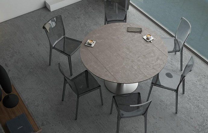 Table de repas ronde extensible effet bois entourée de 6 chaises grises anthracites