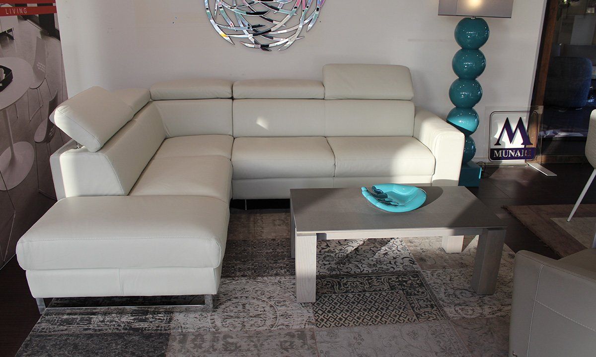 Canapé d'angle en cuir blanc de la marque Vittoria avec table basse grise et ojet de décoration bleu