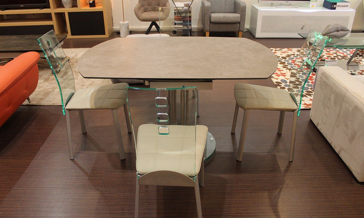 Table de repas rectangulaire extensible de la marque Pérouse entourée de 4 chaises en cuir blanc et dossier transparent