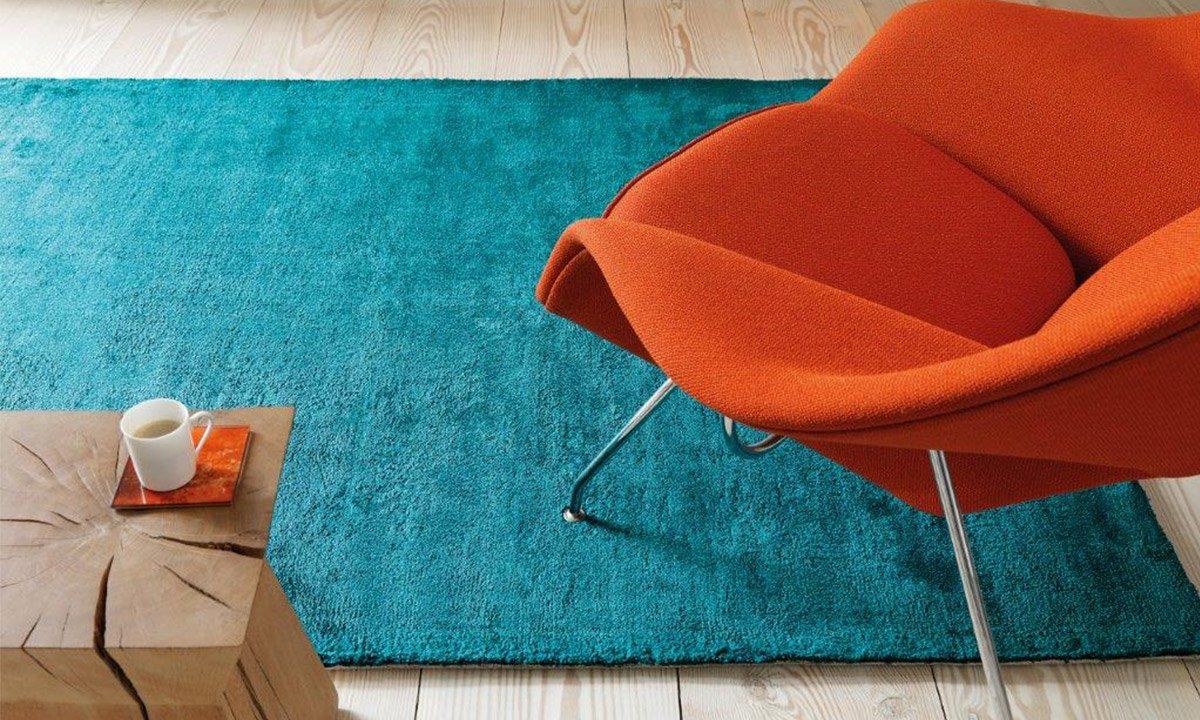 Tapis bleu en dessous d'un fauteuil en tissu
