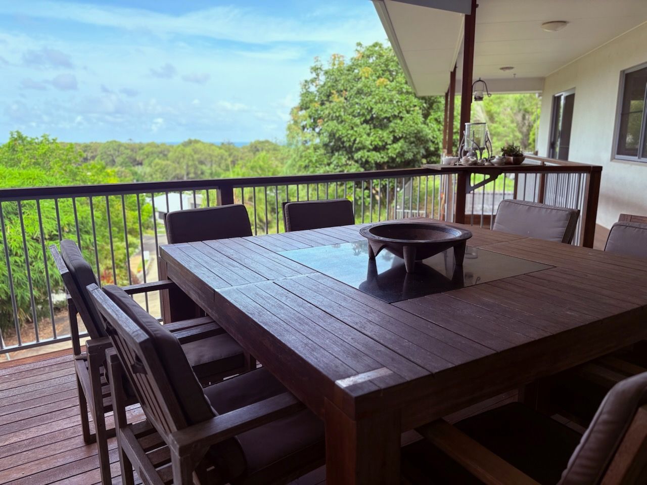 A wooden table and chairs on a balcony overlooking a forest.