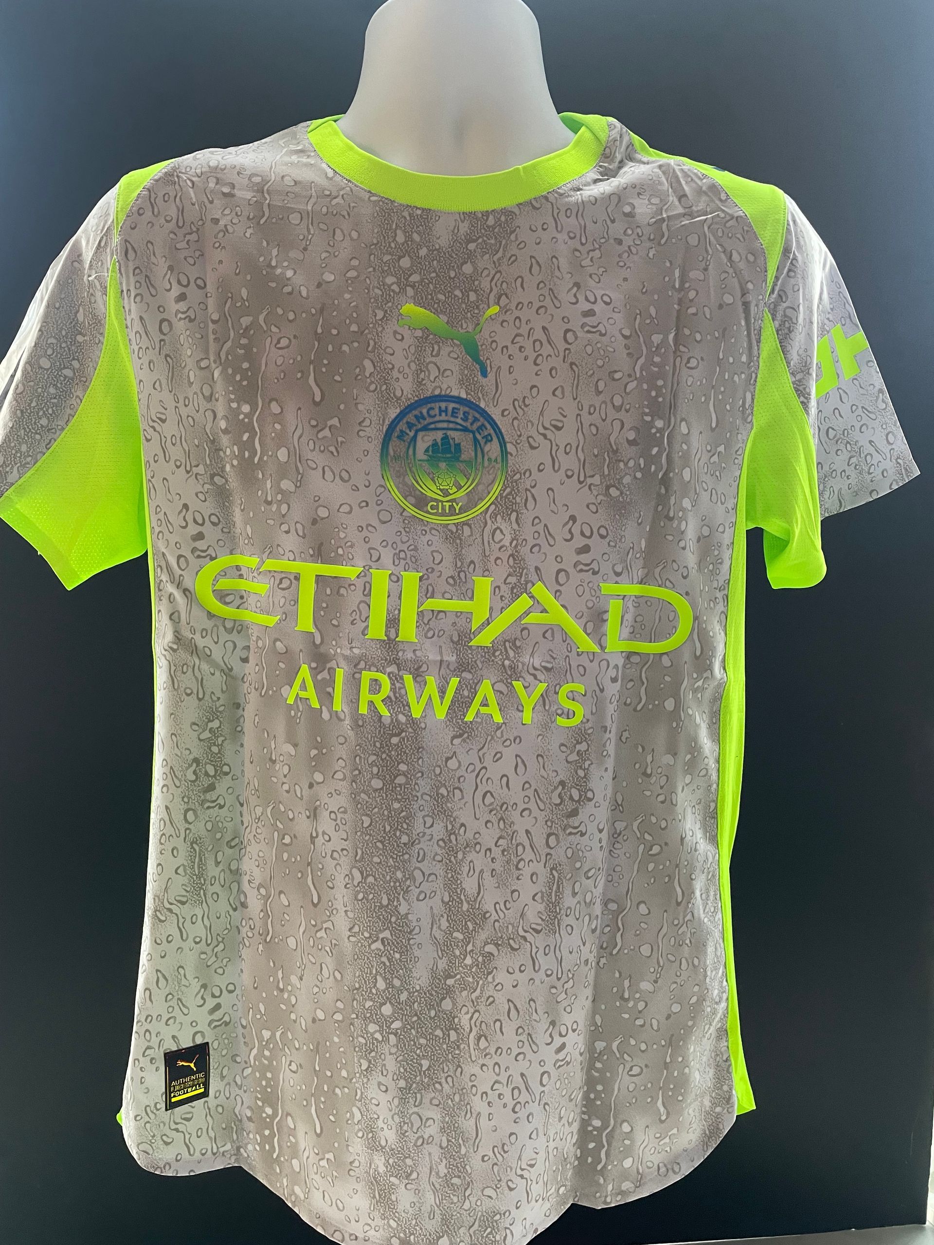 Gray and neon green Etihad Airways soccer jersey on a mannequin, front view