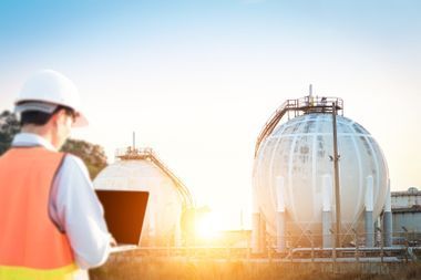 Rakennustyöntekijä säiliöiden edessä