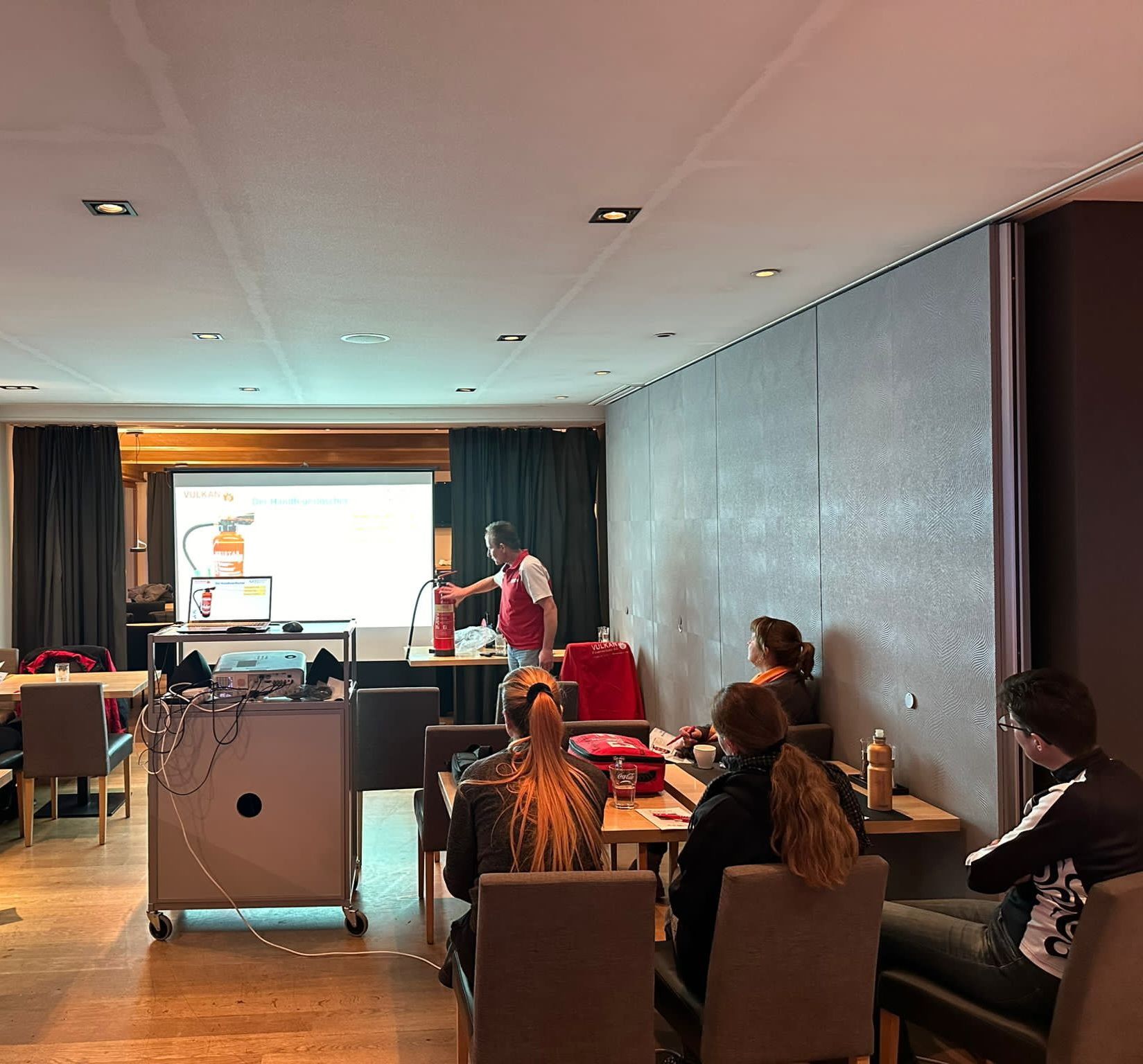 Eine Gruppe von Menschen sitzt in einem Raum und sieht sich eine Präsentation an