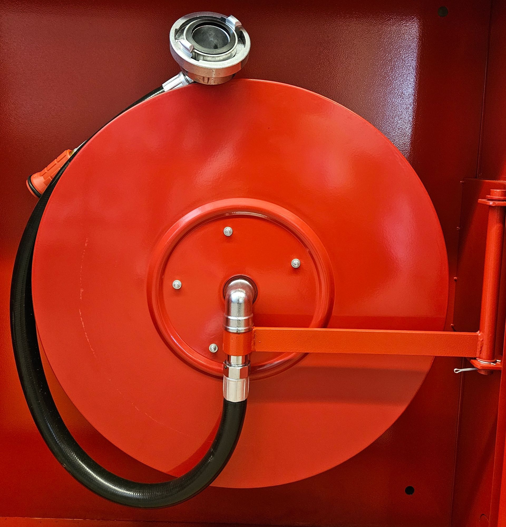 Eine rote Feuerwehrschlauchtrommel mit einem daran befestigten schwarzen Schlauch