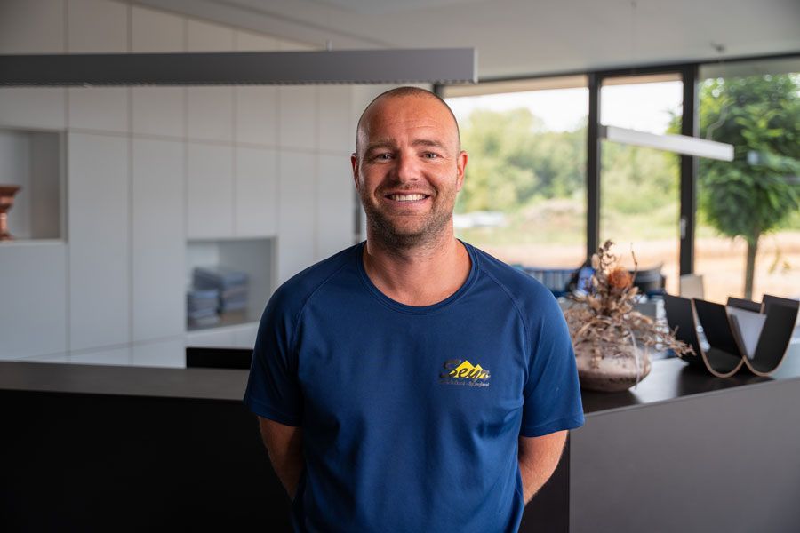 Ein Mann in einem blauen Hemd steht mit verschränkten Armen da.