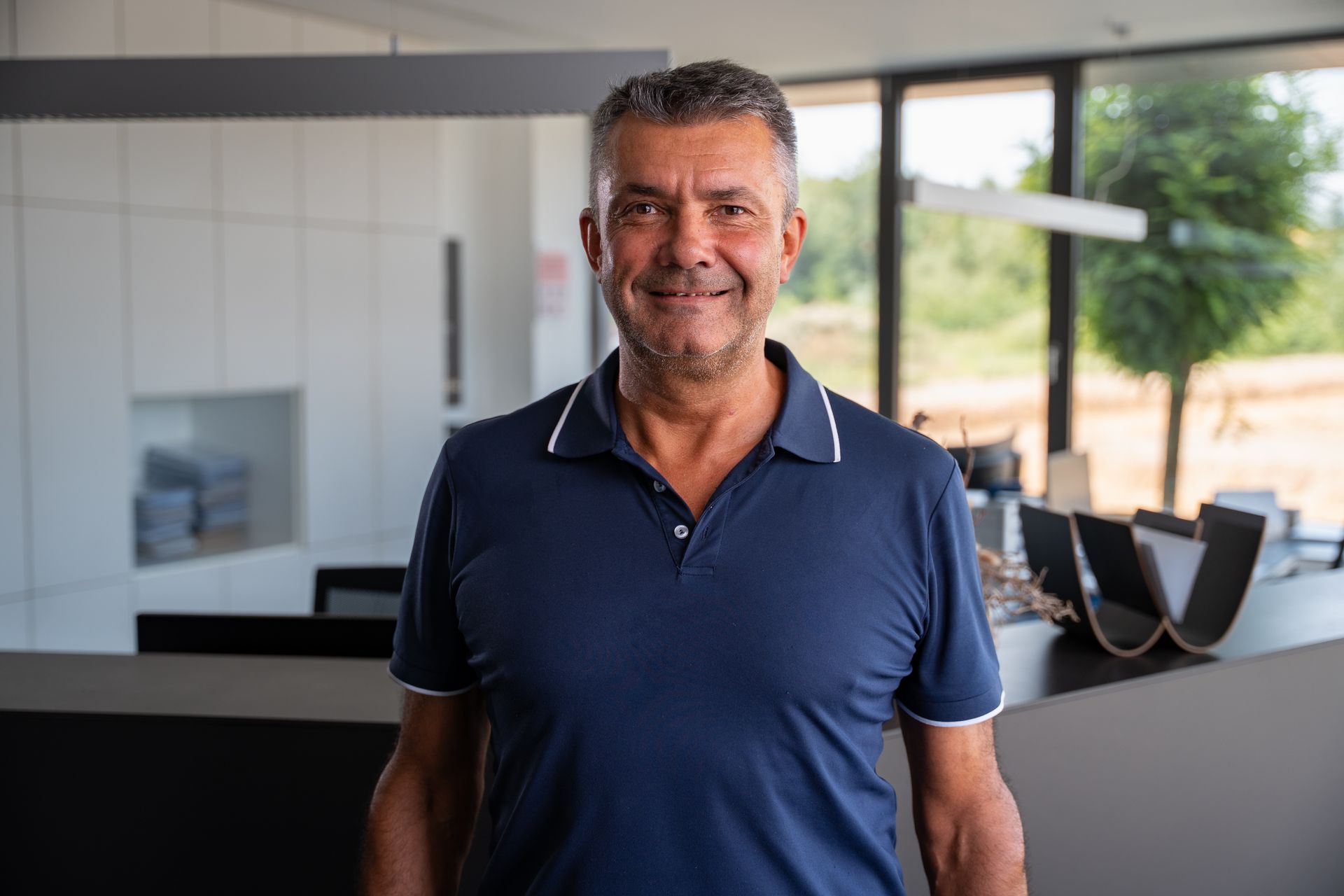 Ein Mann in einem blauen Hemd steht mit verschränkten Armen da.