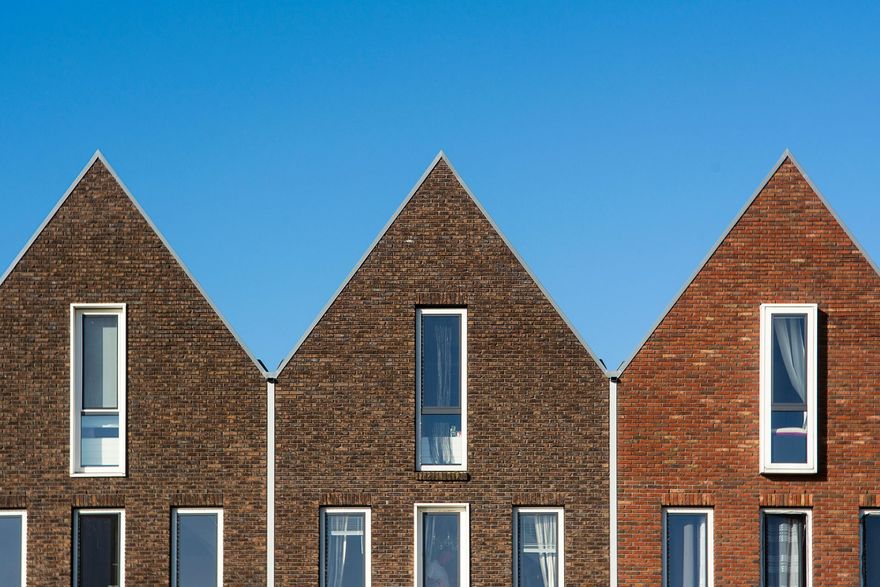 Three brick house rooftops against a clear blue sky
