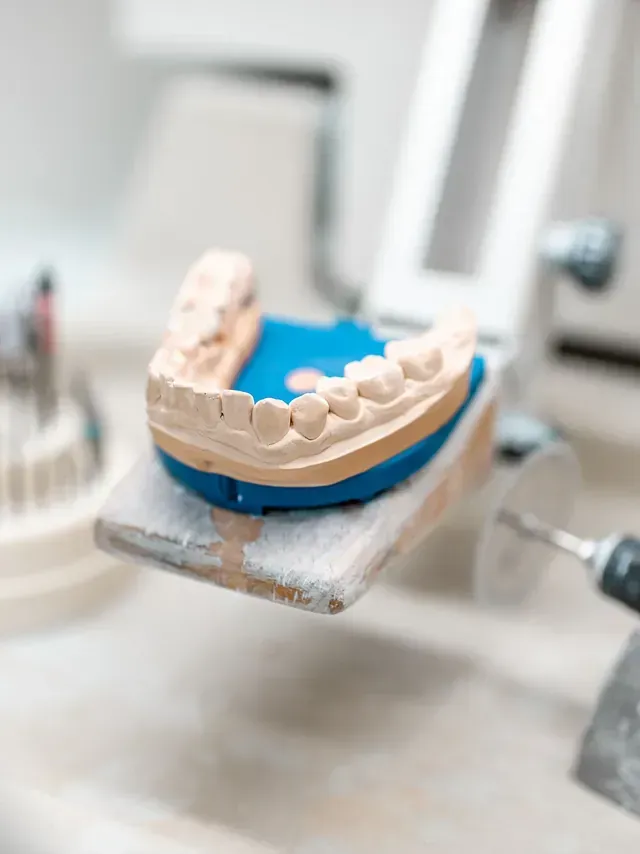 Molde dental de dientes en un soporte, con herramientas y equipo dental en un entorno médico.