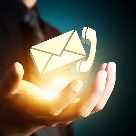 Mano sosteniendo un sobre de correo electrónico brillante y un teléfono, simbolizando las opciones de contacto.