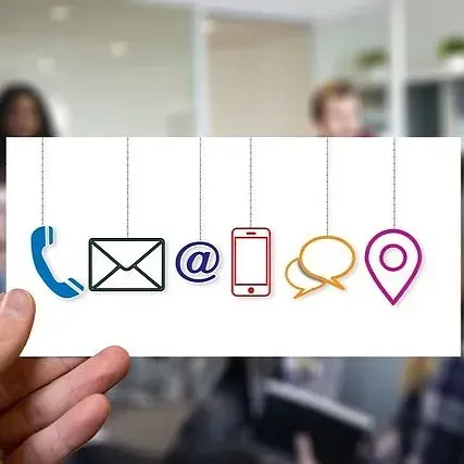 Mano sosteniendo una tarjeta con iconos de contacto: teléfono, correo electrónico, dirección, mensajería.