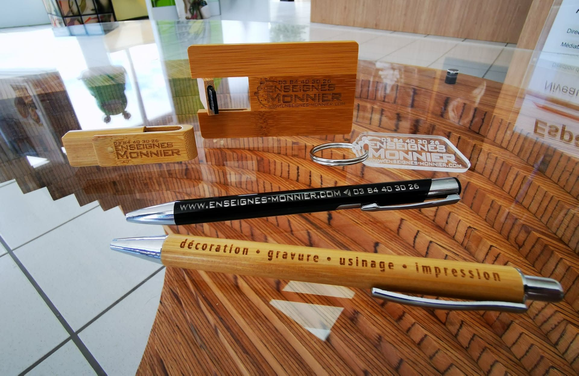 Objets de bureau en bois : stylo, règle et plaques nominatives gravées.