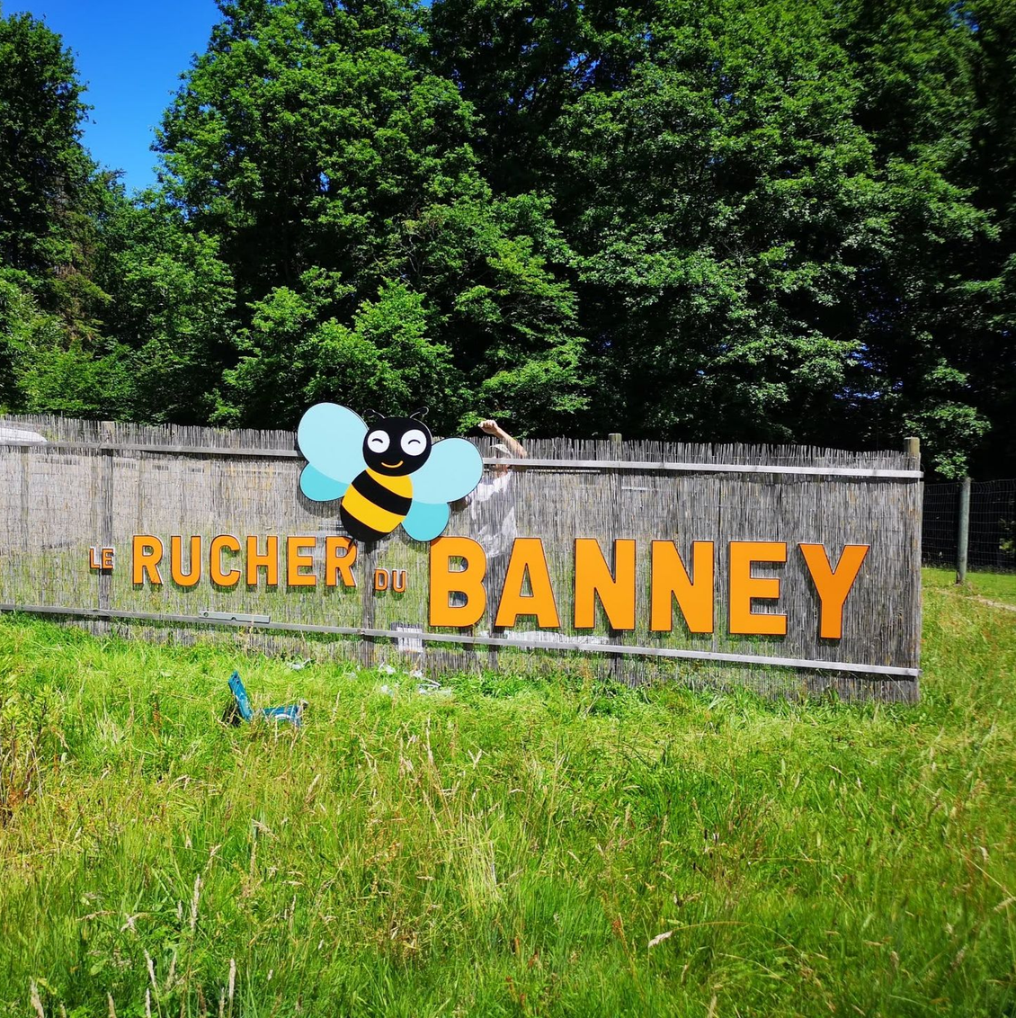 Panneau en bois sur une clôture et orné d'une abeille dessinée.