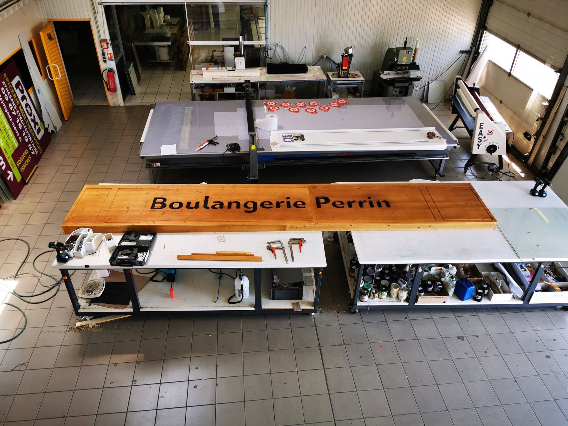 Atelier de l'entreprise, avec un long convoyeur et une enseigne en bois.