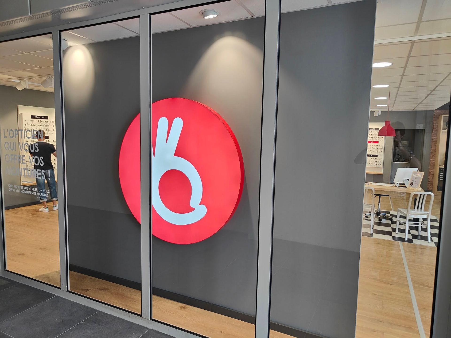 Un grand logo circulaire rouge sur un mur sombre à l'intérieur d'une boutique vitrée.