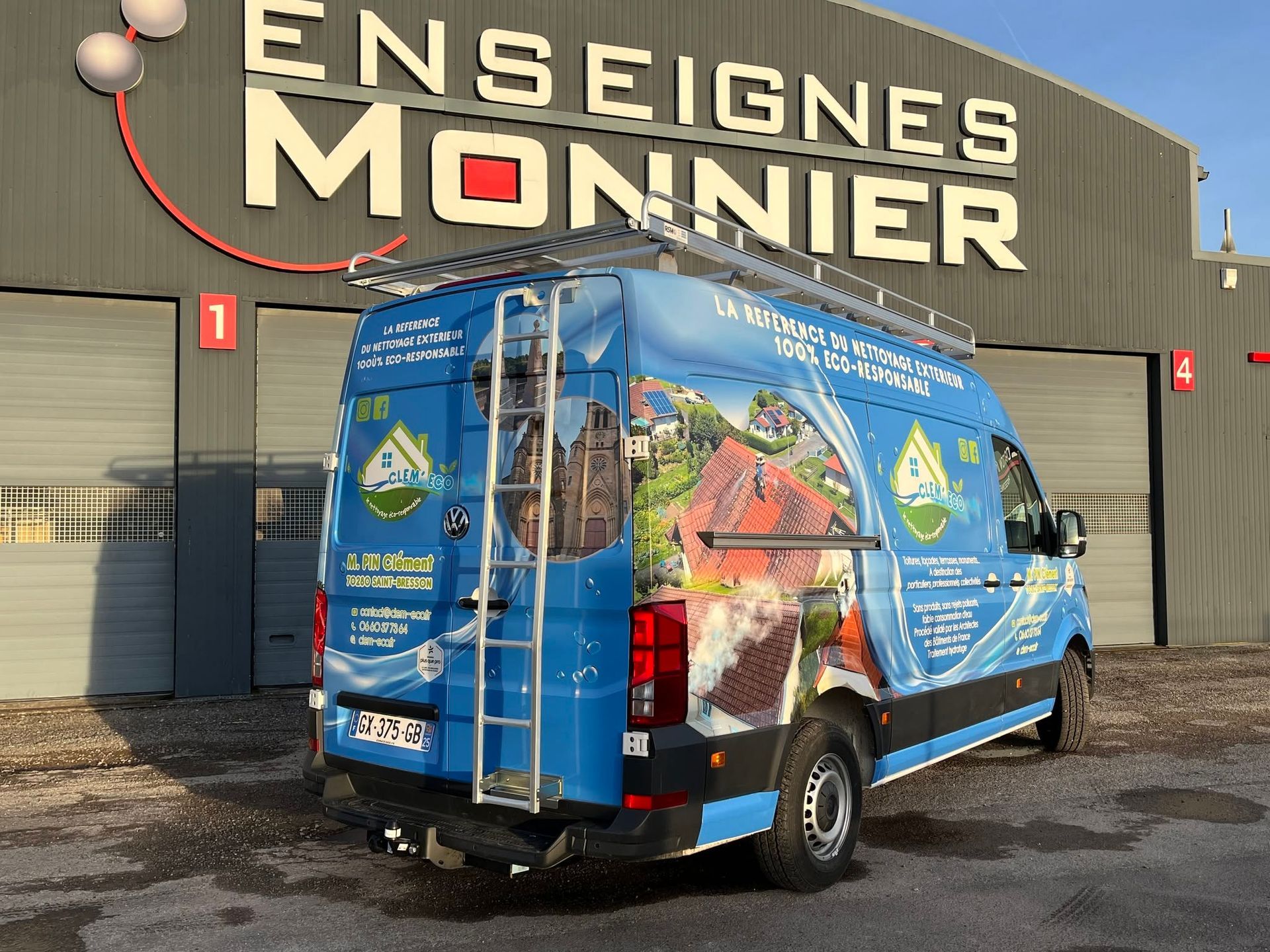 Une camionnette floquée au nom de l'entreprise est garée devant un bâtiment.