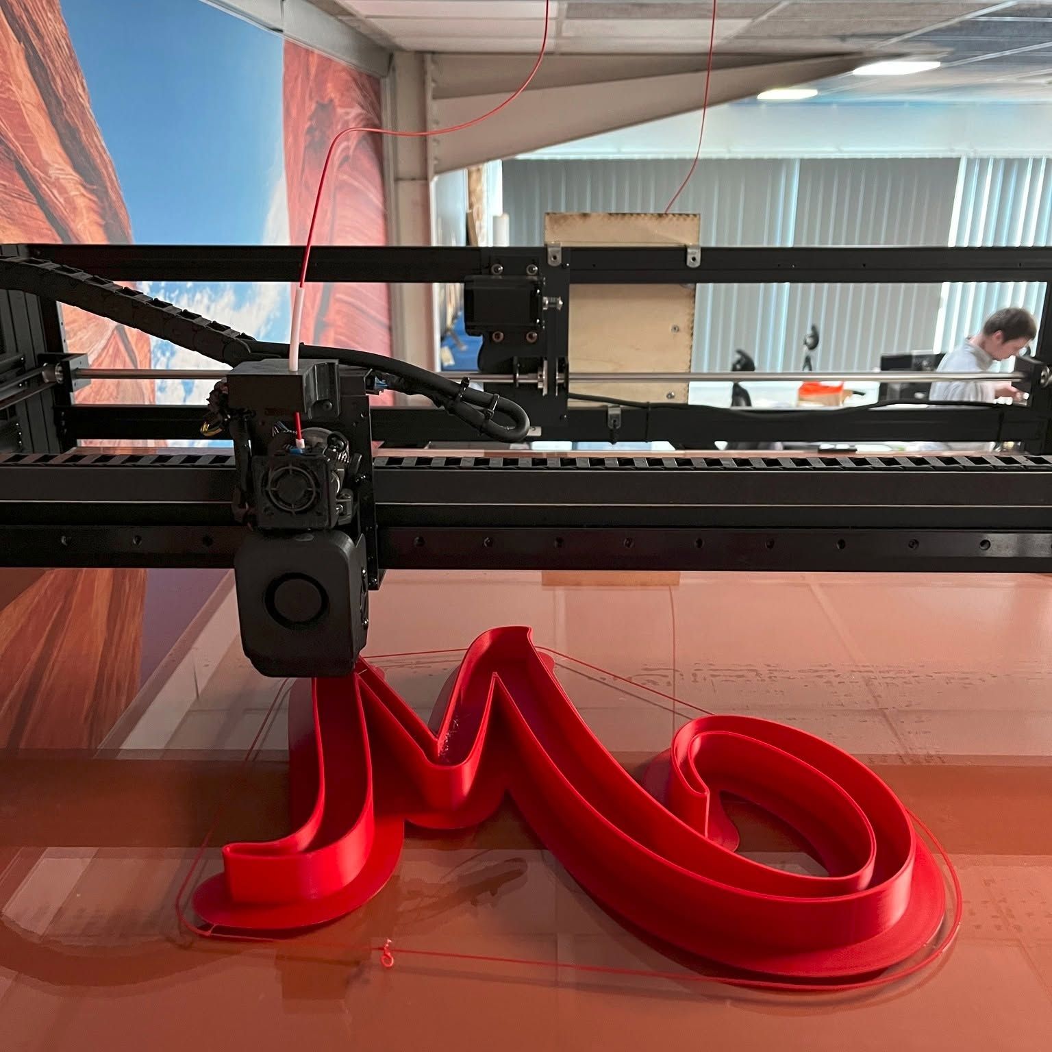 Imprimante 3D imprimant un motif brillant en forme de cœur rouge sur le plateau de construction.