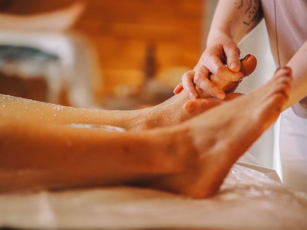 Une personne se fait faire une manucure avec du vernis à ongles rose sur une table de salon