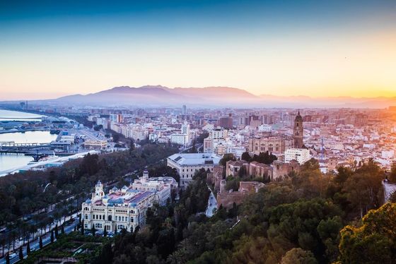 Una vista aérea de una ciudad al atardecer con montañas al fondo.