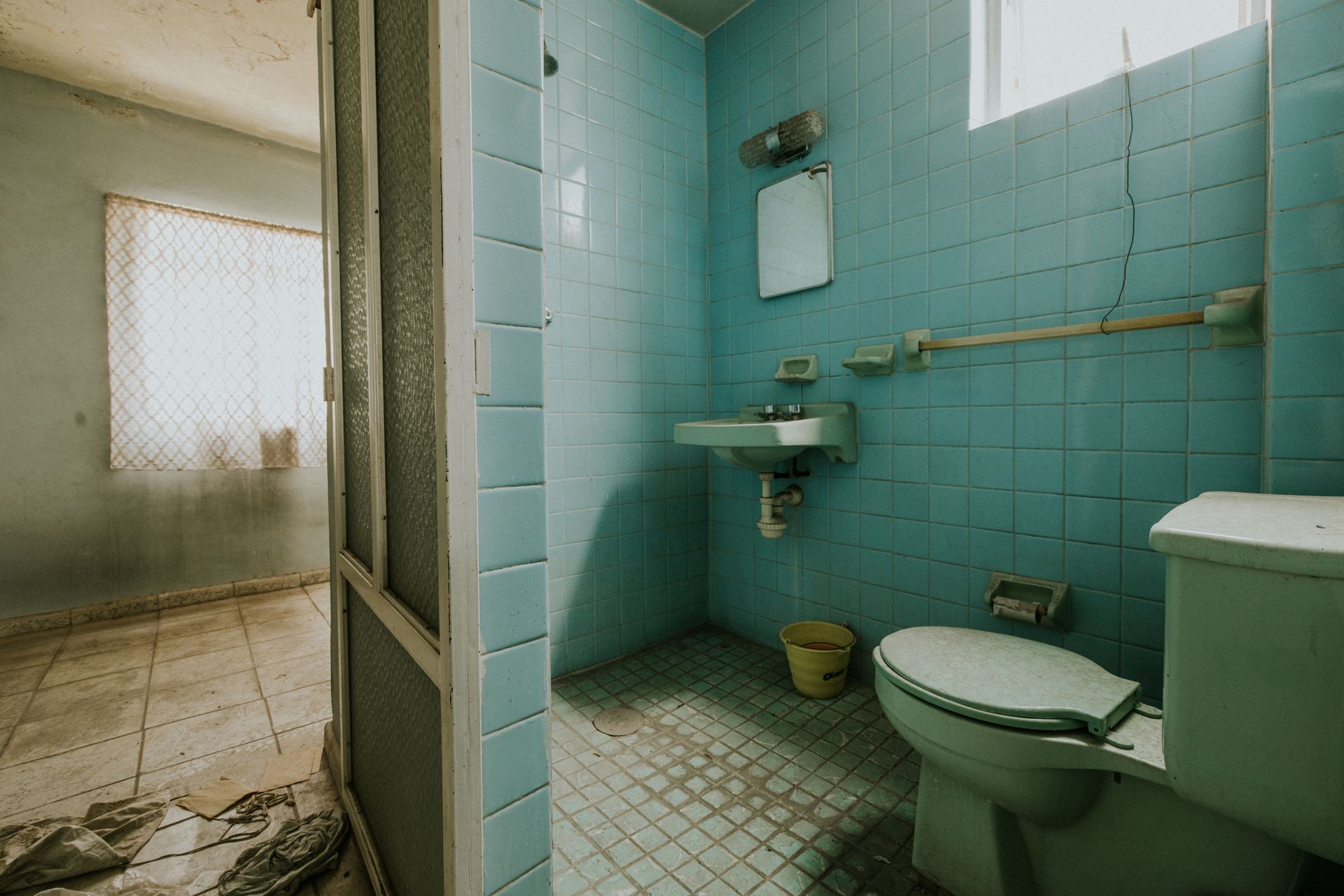 Vieille salle de bains sale avec carrelage bleu, toilettes, lavabo 