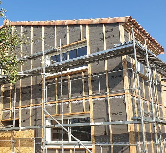 Extérieur de maison sur un chantier avec des échafaudages pour une construction en ossature en bois