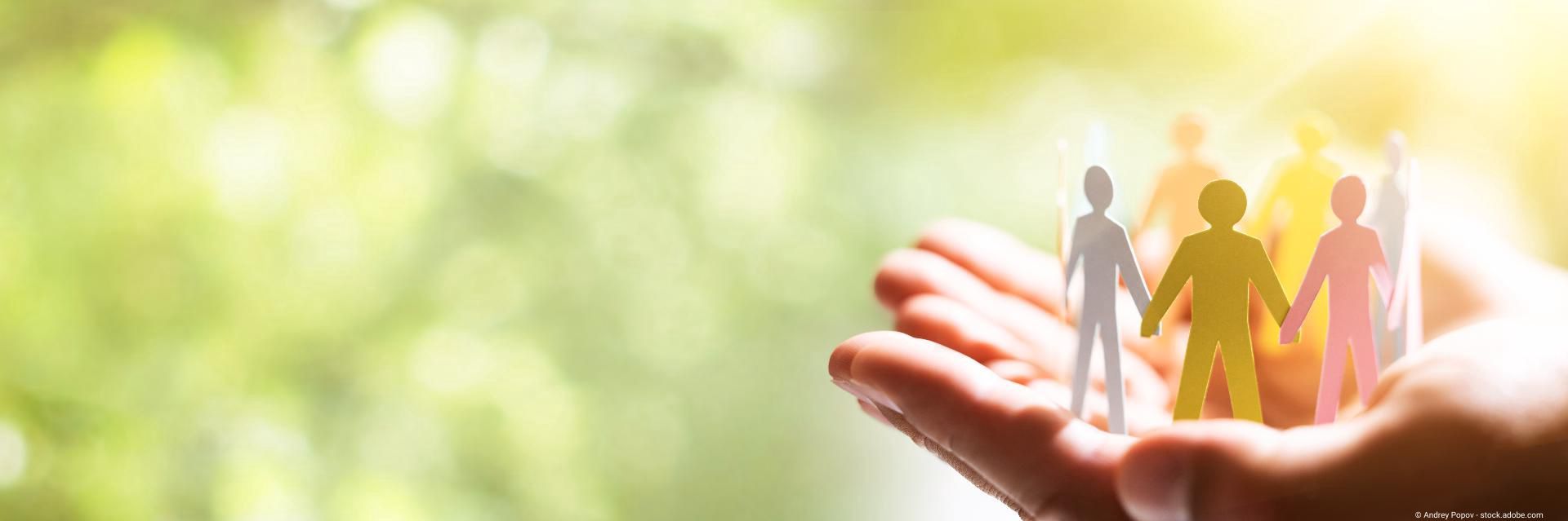 Hände halten symbolische Papierfiguren.