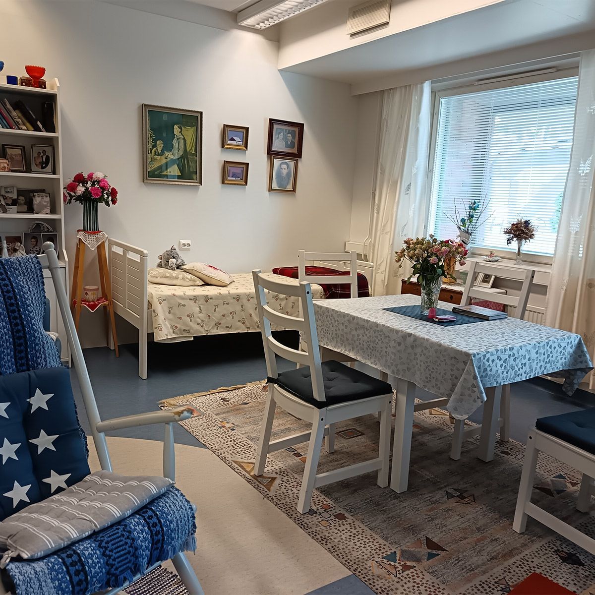 Viihtyisä huone, jossa on sänky, pöytä, tuoleja ja keinutuoli.