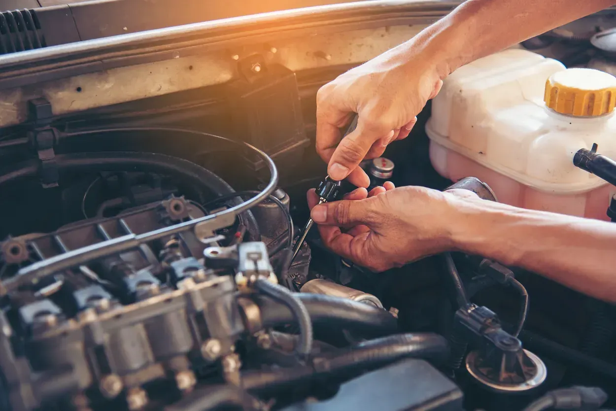 Un hombre está trabajando en el motor de un coche.