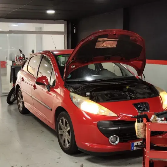 Un coche rojo con el capó levantado en un garaje