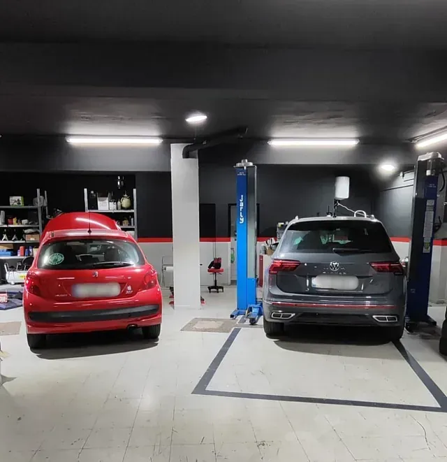 Un coche rojo y un coche gris están aparcados en un garaje.