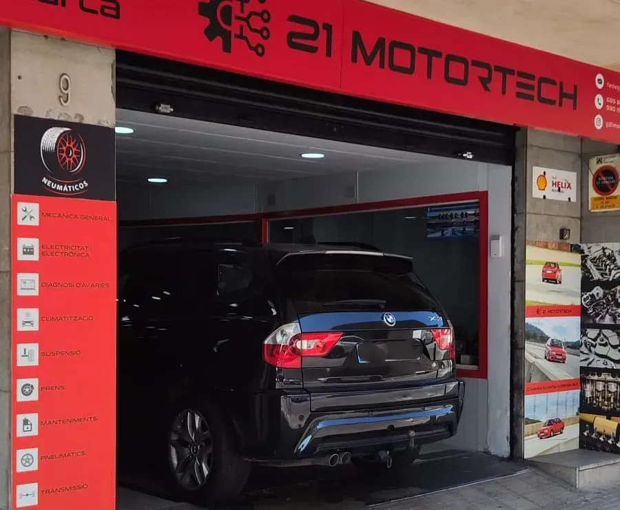 Un coche está aparcado delante de una tienda llamada 21 motortech
