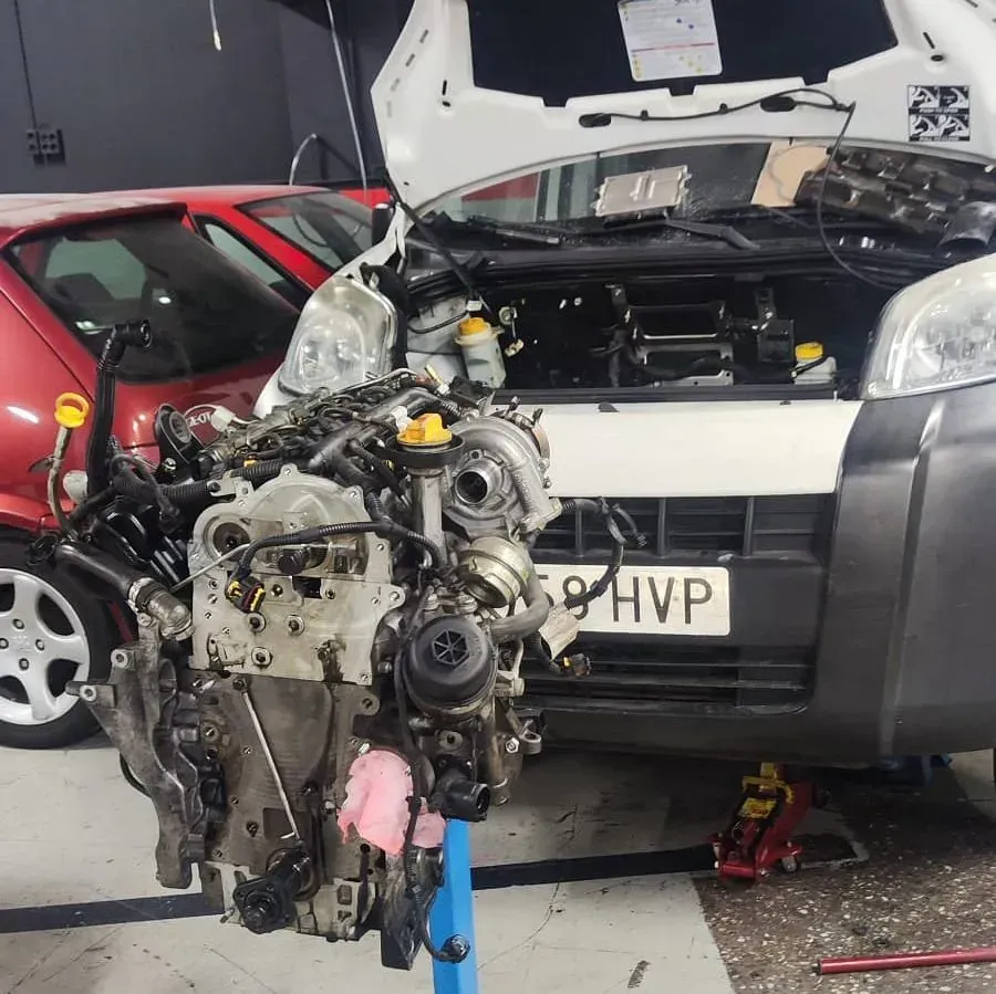 Un coche con el capó levantado tiene una matrícula que dice hvp