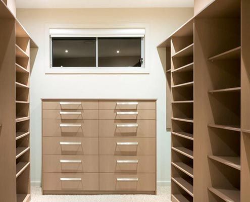 Vestidor con estanterías, cajones y ventana en color beige.