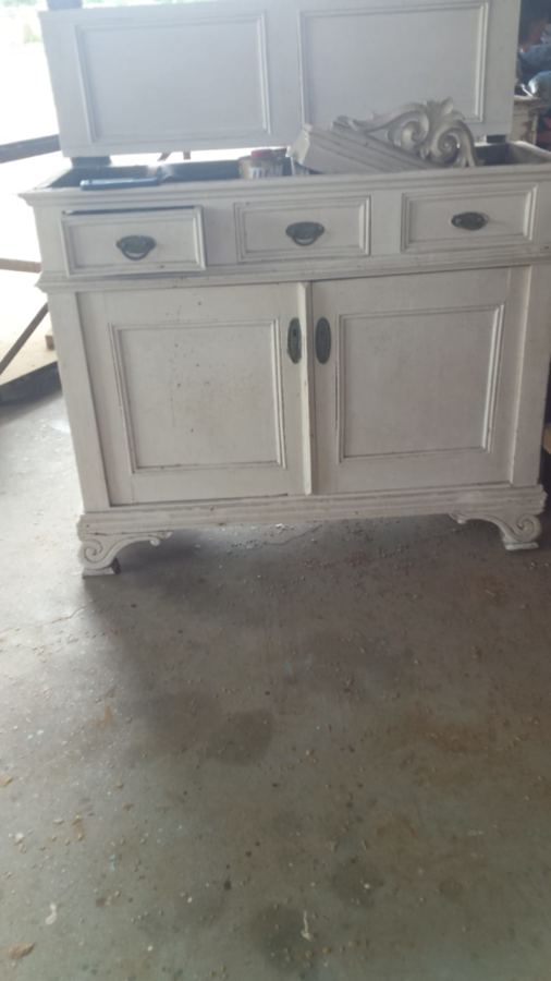 Mueble pintado de blanco con dos puertas, tres cajones y herrajes negros.