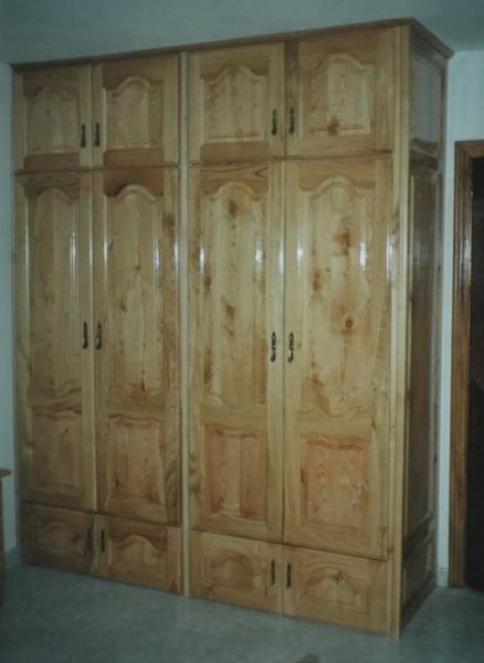 Armario de madera con múltiples puertas y cajones, en una habitación.