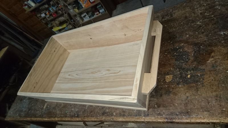Caja de madera con asa sobre banco de trabajo.
