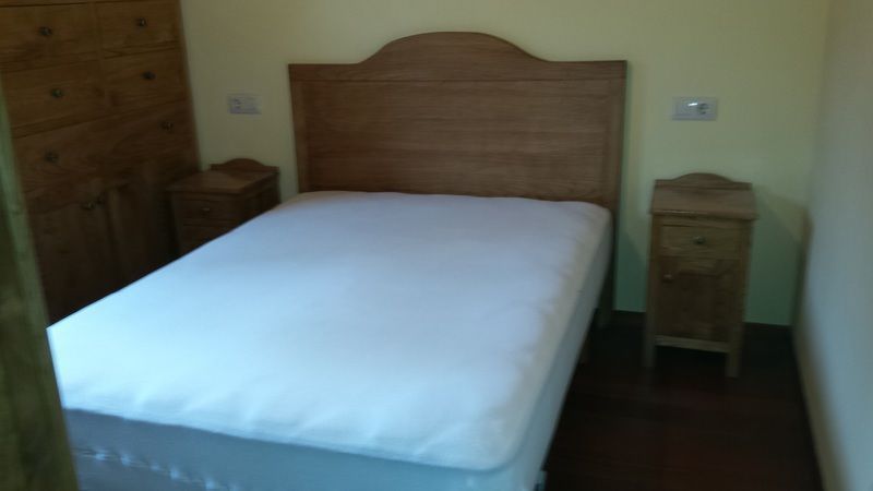 Dormitorio con cama, dos mesitas de noche, cabecero de madera y armario.