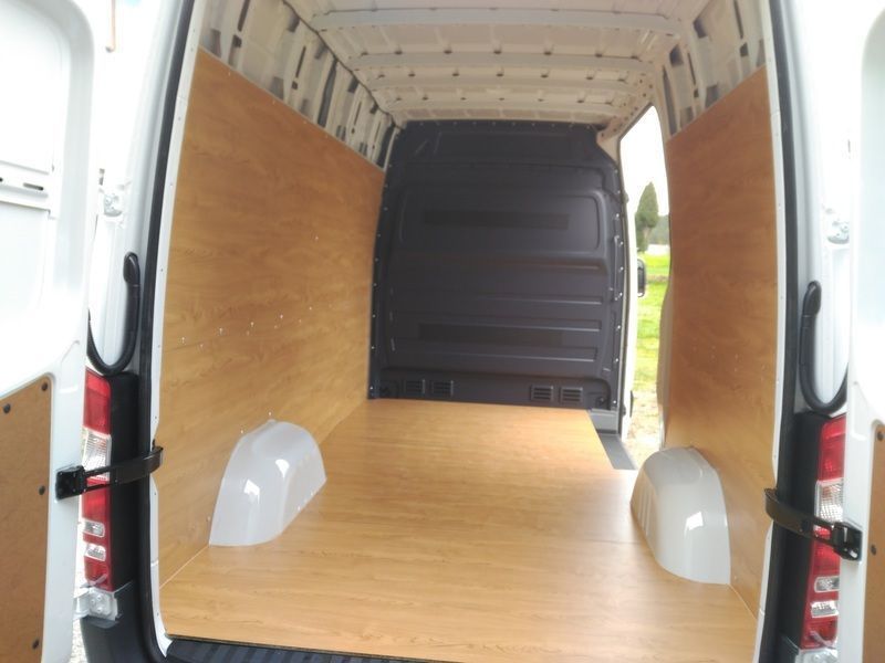 Interior de una furgoneta de carga blanca, con suelo y paredes de madera. Puertas traseras abiertas.