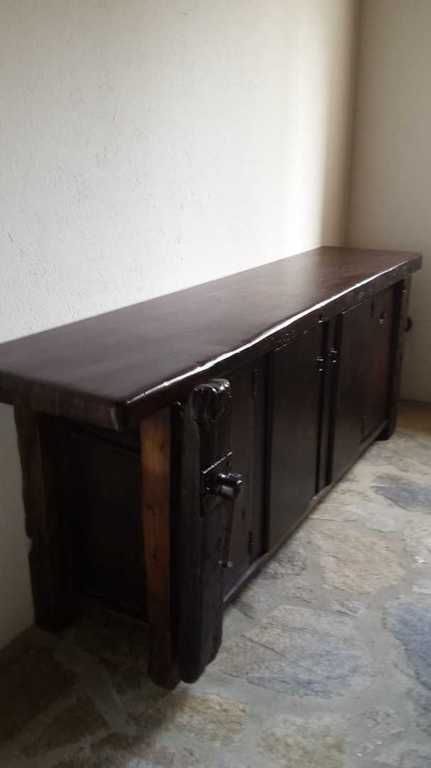 Armario de madera oscura contra una pared blanca en una habitación. Tiene dos puertas y tiradores ornamentados.