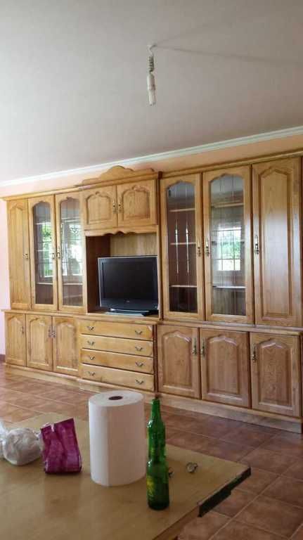 Centro de entretenimiento de madera con TV, cajones y gabinetes con frente de vidrio en una habitación.