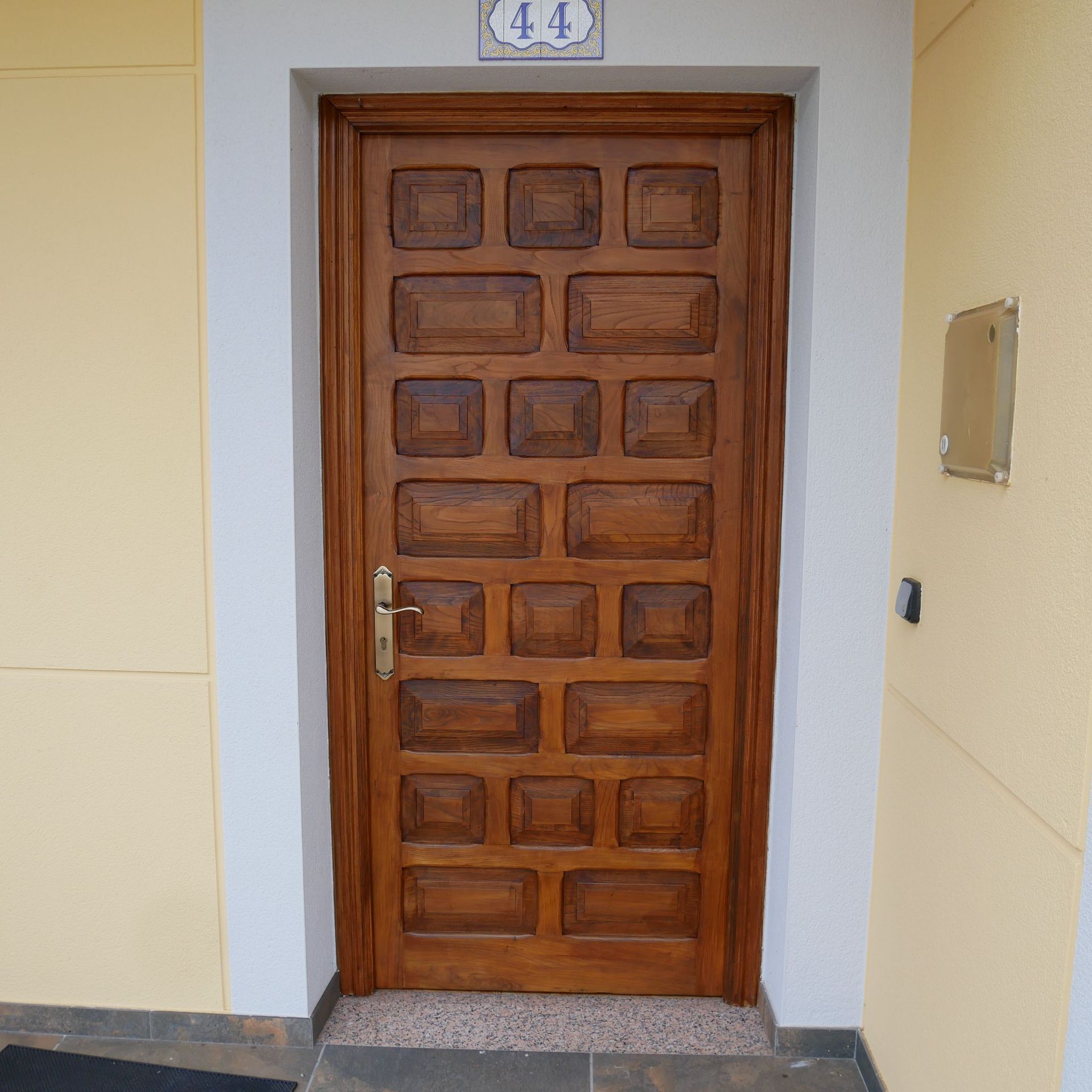 Puerta de madera con paneles rectangulares, dirección número 44 arriba.