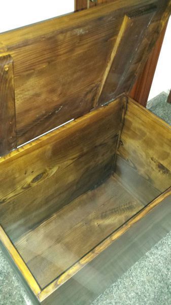 Vista interior de un cofre de madera abierto con interior teñido; tonos marrones.