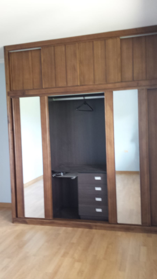 Armario de madera con puertas de espejo, cajonera y perchero. Colores marrón y beige.