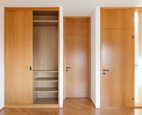 Armario de madera con puerta corrediza, dos puertas de madera y suelo de madera.