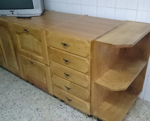 Mueble de madera con cajones, estantes y TV encima en una habitación con azulejos.