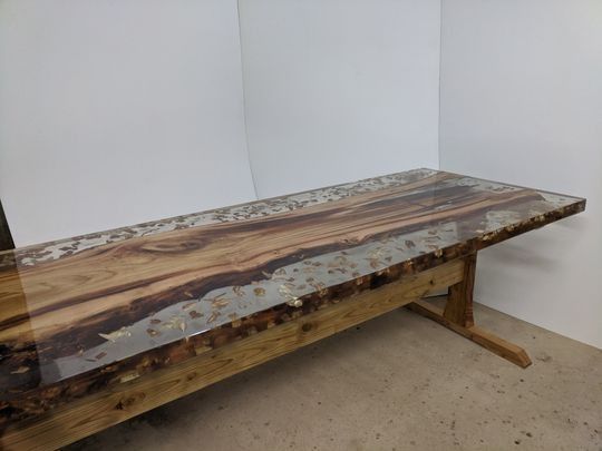 Mesa de comedor de madera con un río de resina transparente en el centro.