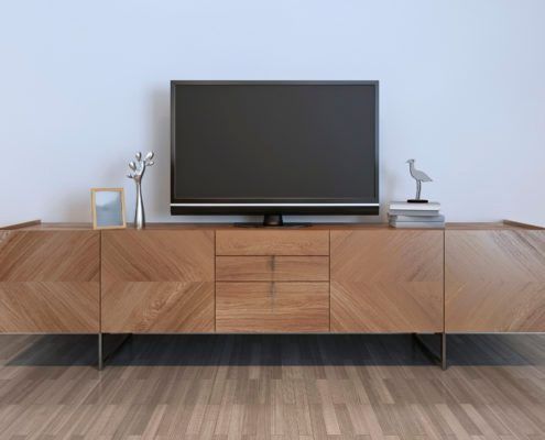 Un mueble de TV de madera con un televisor de pantalla plana montado, decoración y un piso de madera contra una pared blanca.